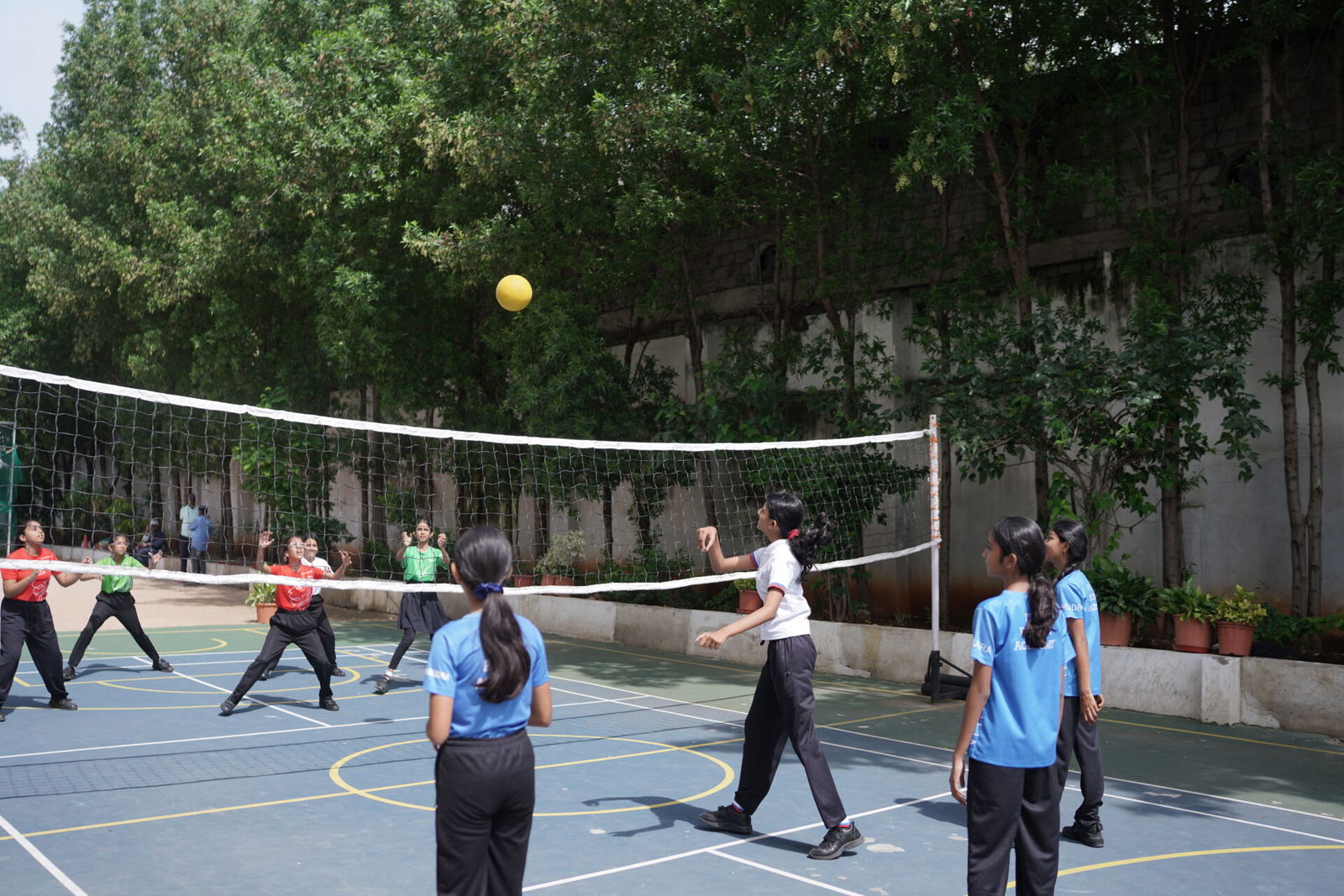 Secondary students playing volleyball on the outdoor school court during a physical education class