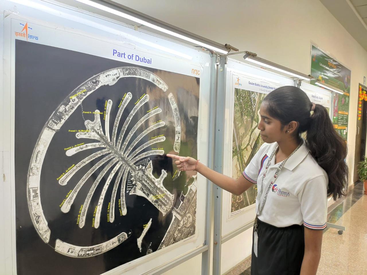 student points at a satellite map of the Palm Jumeirah in Dubai at a science fair